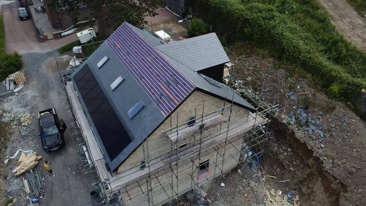 Aerial view of a house being re-roofed with underlay exposed, solar panels and scaffolding