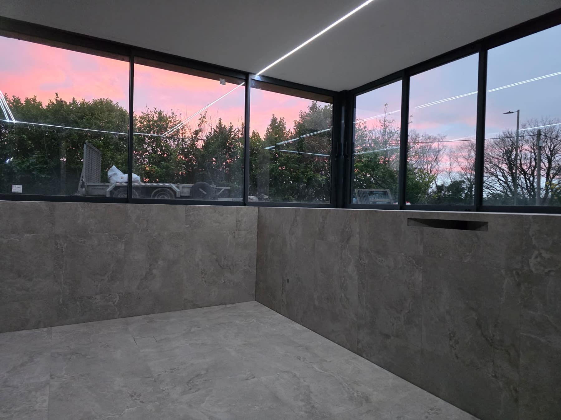 Newly finished room with floor-to-ceiling corner windows overlooking South Wales countryside at dusk