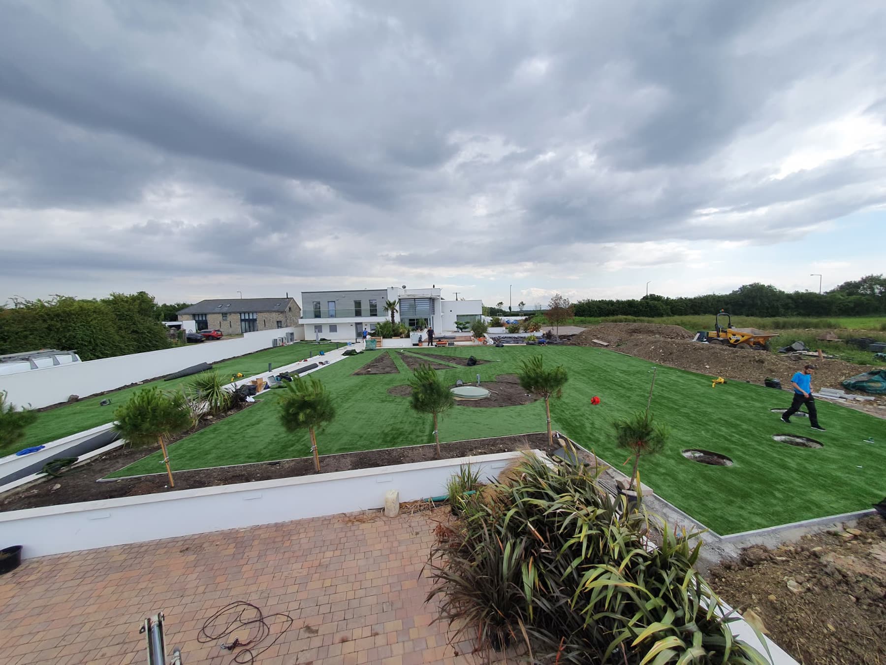 Aerial view of freshly laid lawn and new planting beside a modern house