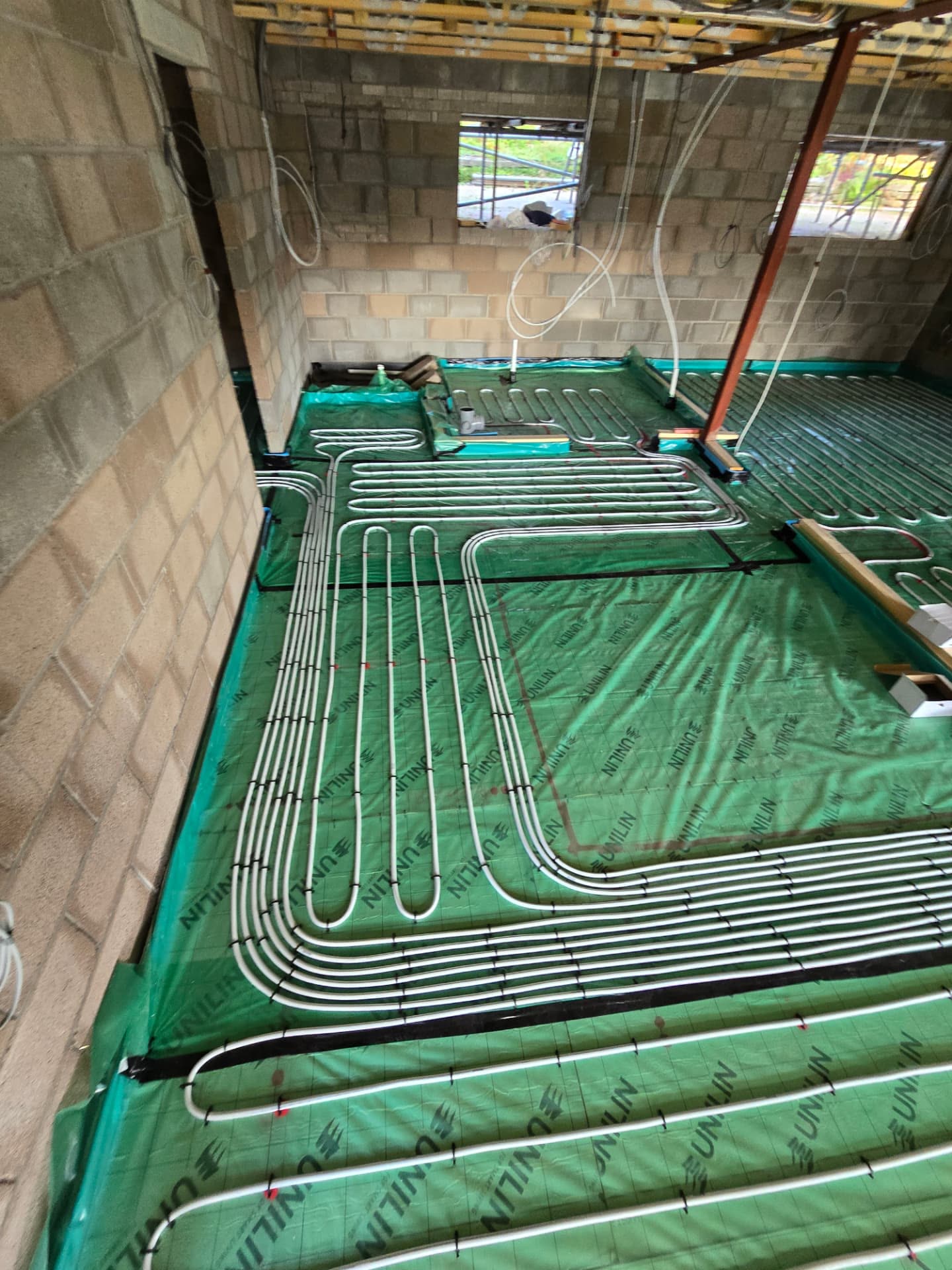 Underfloor heating manifold with pipework spread across insulation during first fix