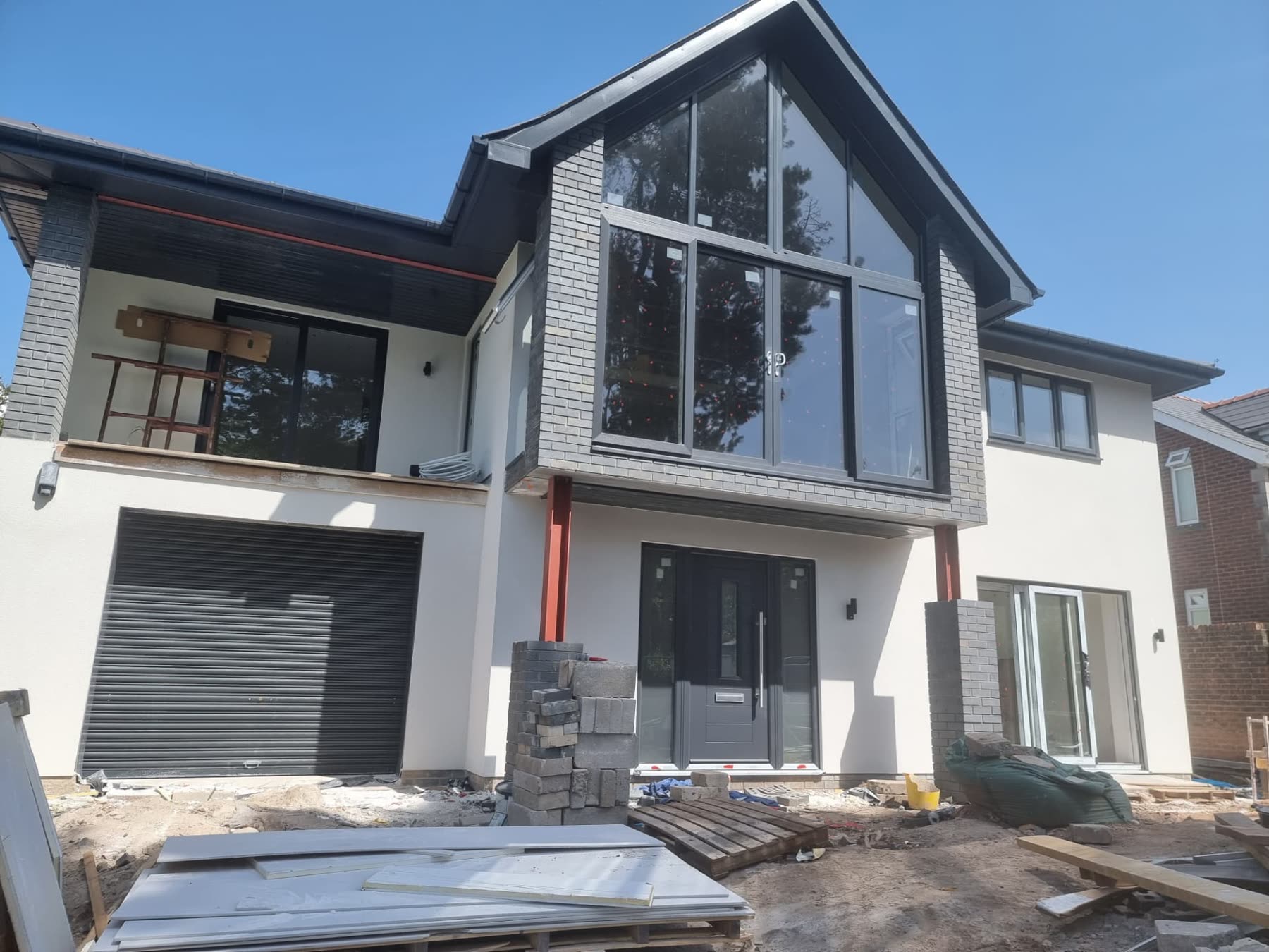 Two-storey house extension mid-build with a large glazed gable window and steel supports