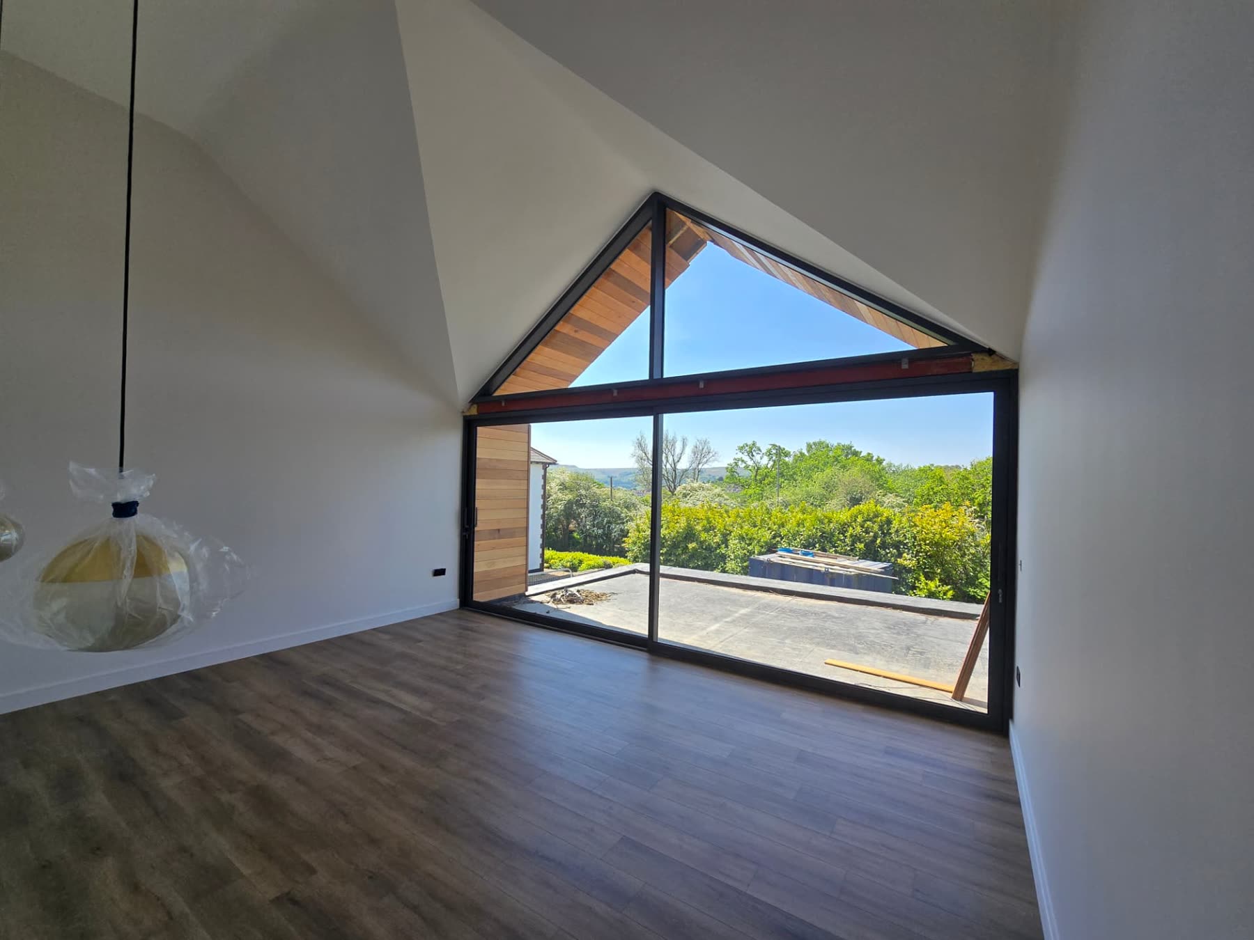 Vaulted bedroom with triangular glazed gable window overlooking open countryside
