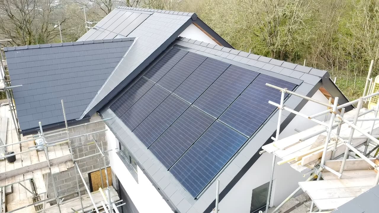 Aerial close-up of a dark solar panel array set into grey slate roof tiles