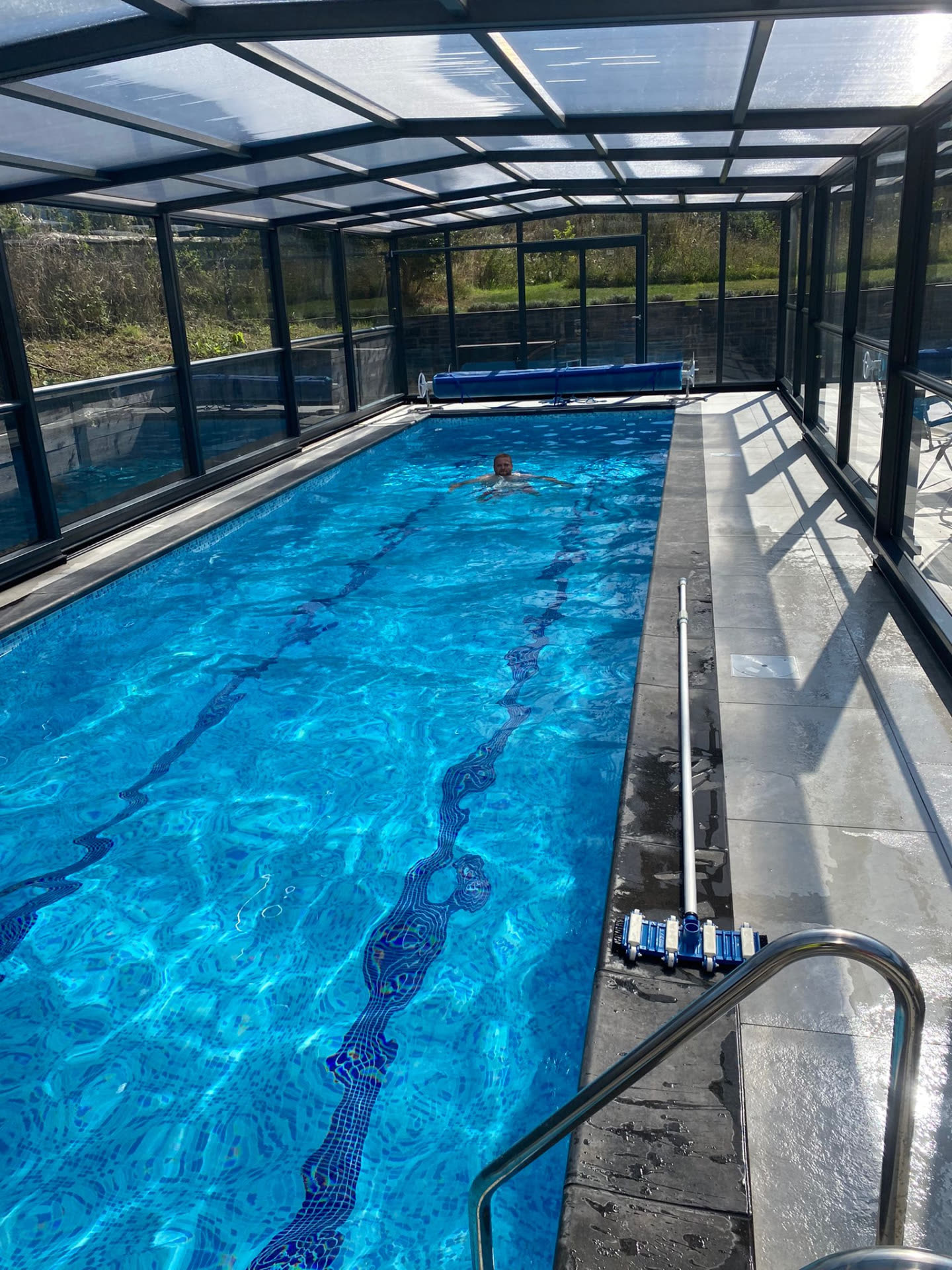 Covered indoor lap pool with retractable roof and poolside decking in use