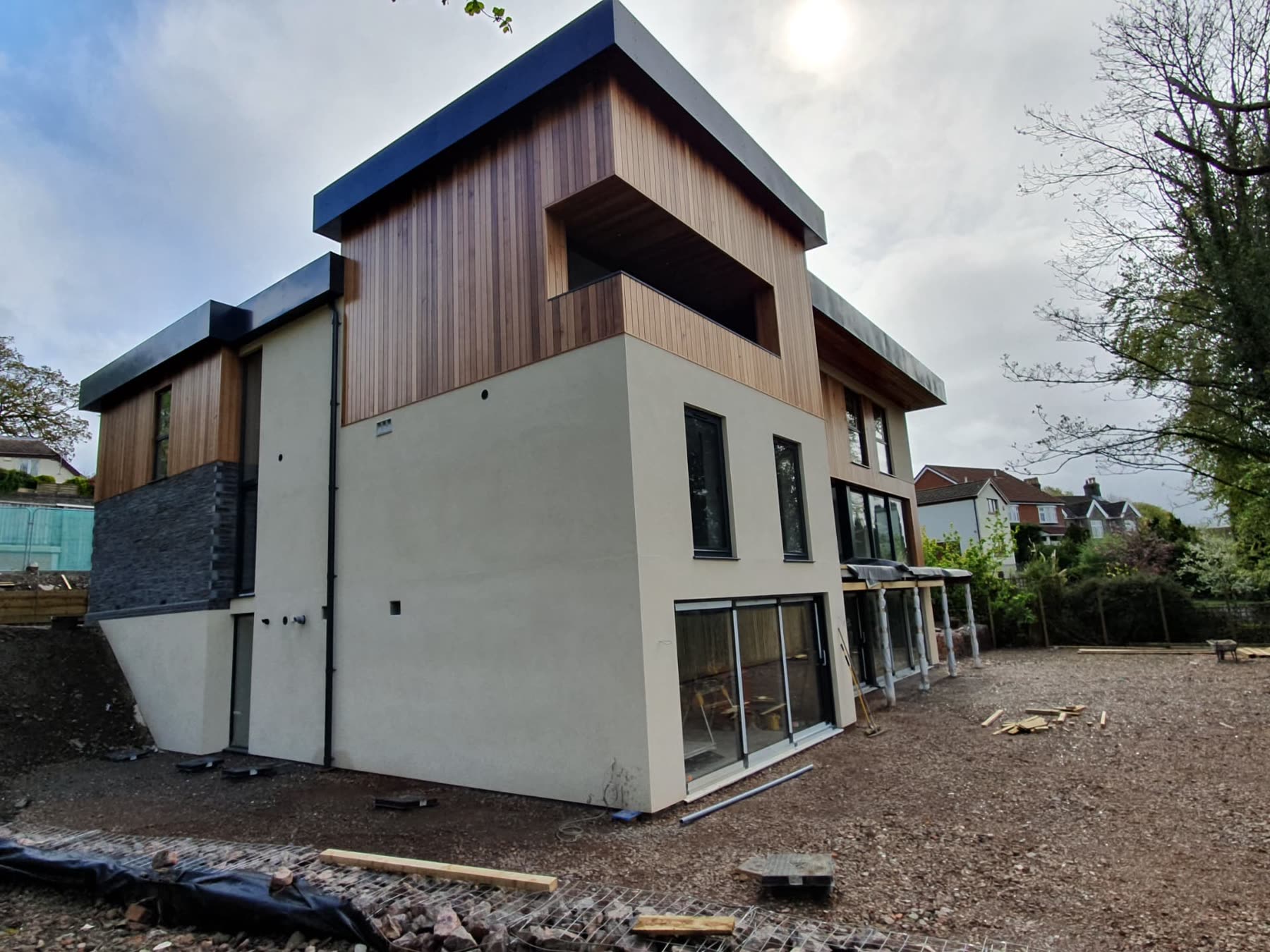 Cedar-clad bespoke home nearing completion with render and large glazed openings