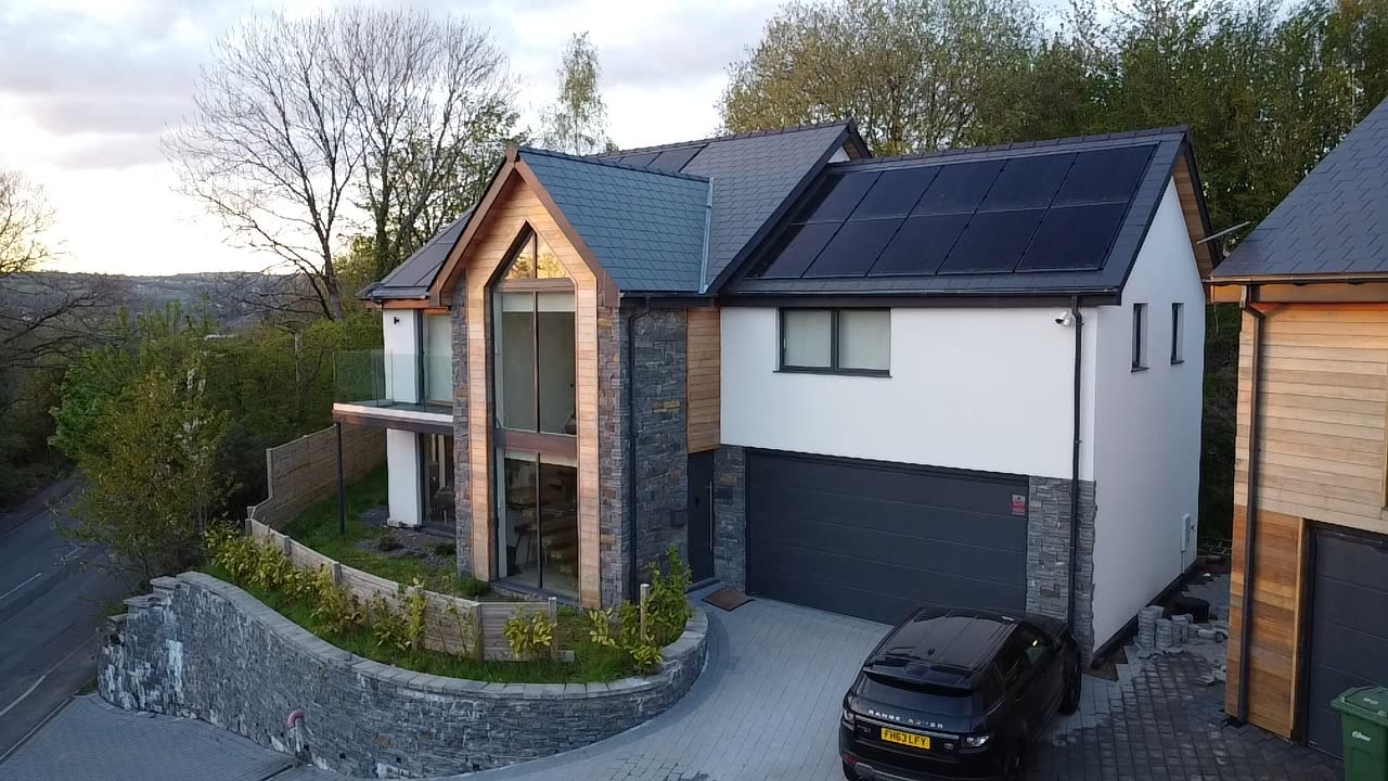 Completed bespoke home photographed from the air at dusk with in-roof solar panels