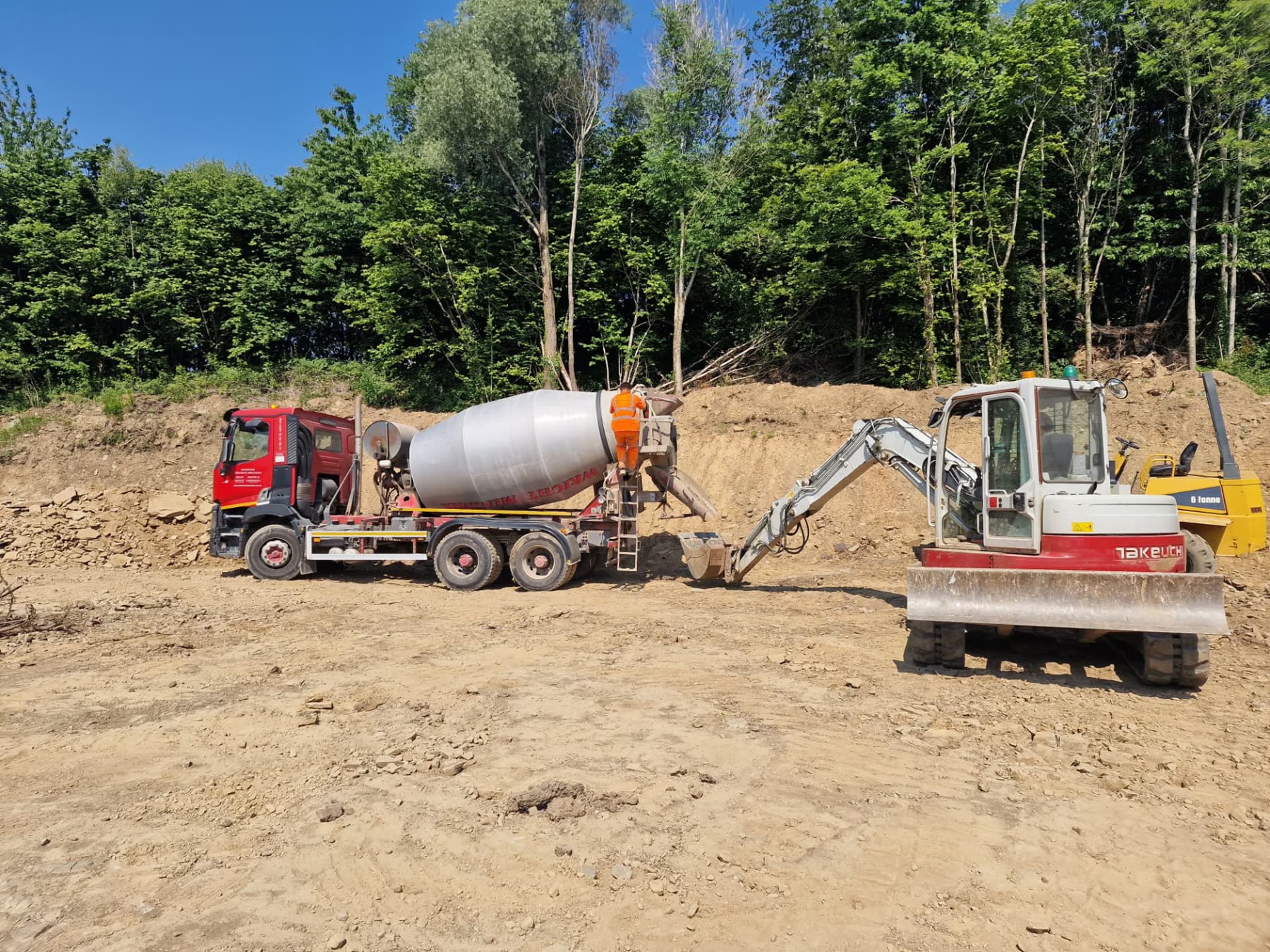 Excavator and concrete mixer working on drainage and substructure works on site