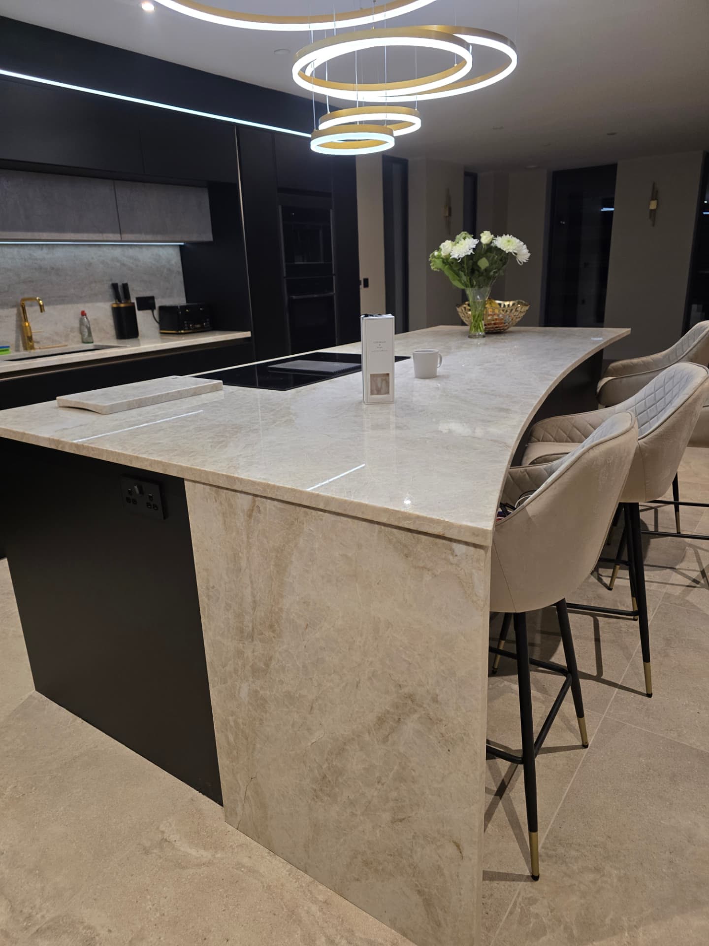 Dark matte kitchen with a marble island, brass accents and fully integrated appliances