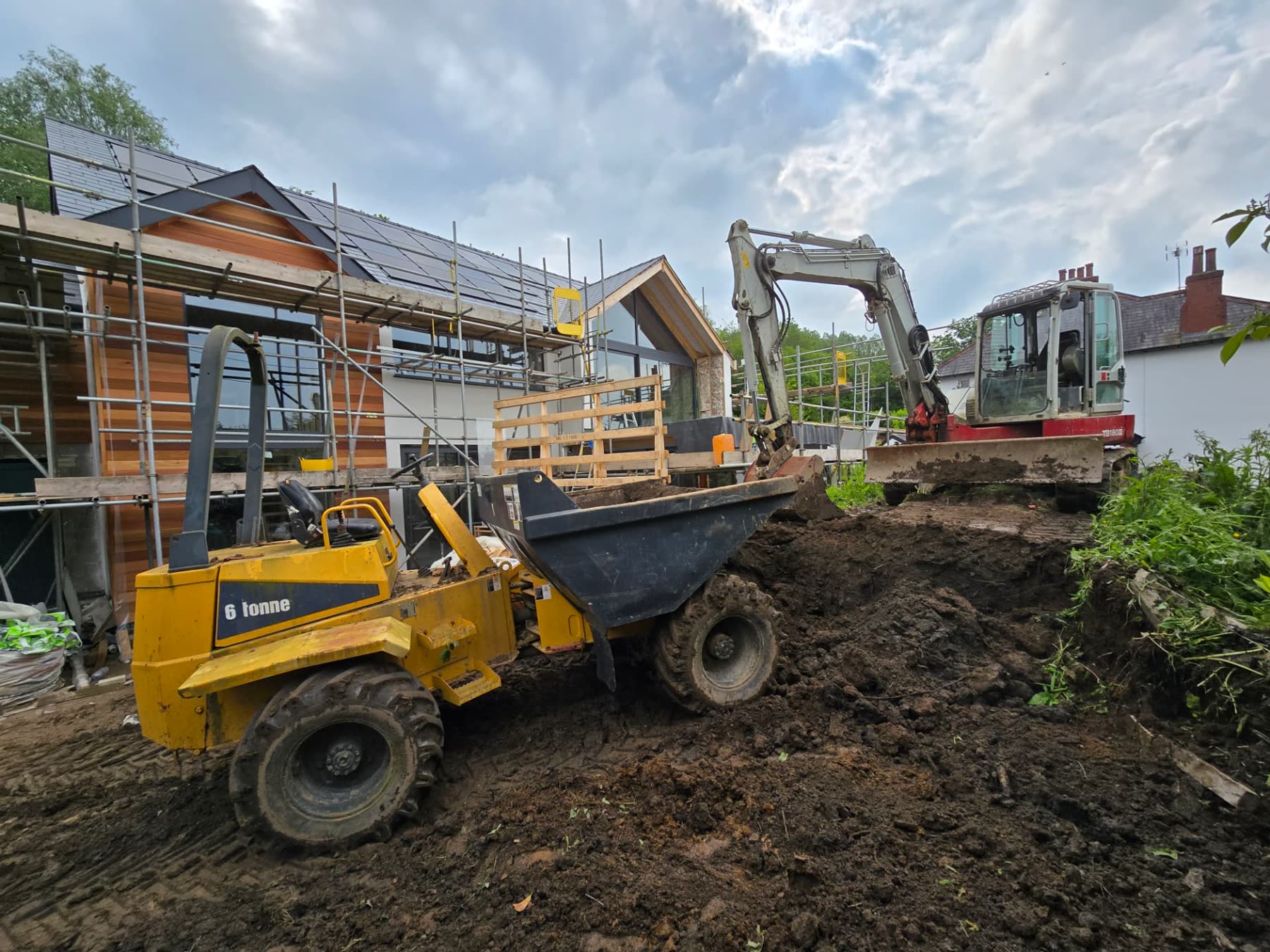 Excavator and dumper moving earth during groundworks on a South Wales construction site