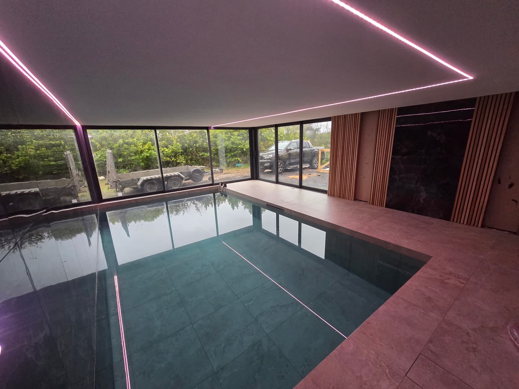 Indoor swimming pool area with timber slat wall, LED strip lighting and glazed corner