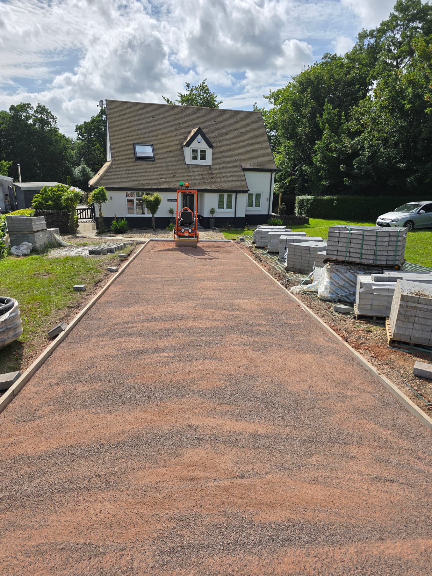 Completed grey block-paved driveway with dark border edging leading to a bespoke home