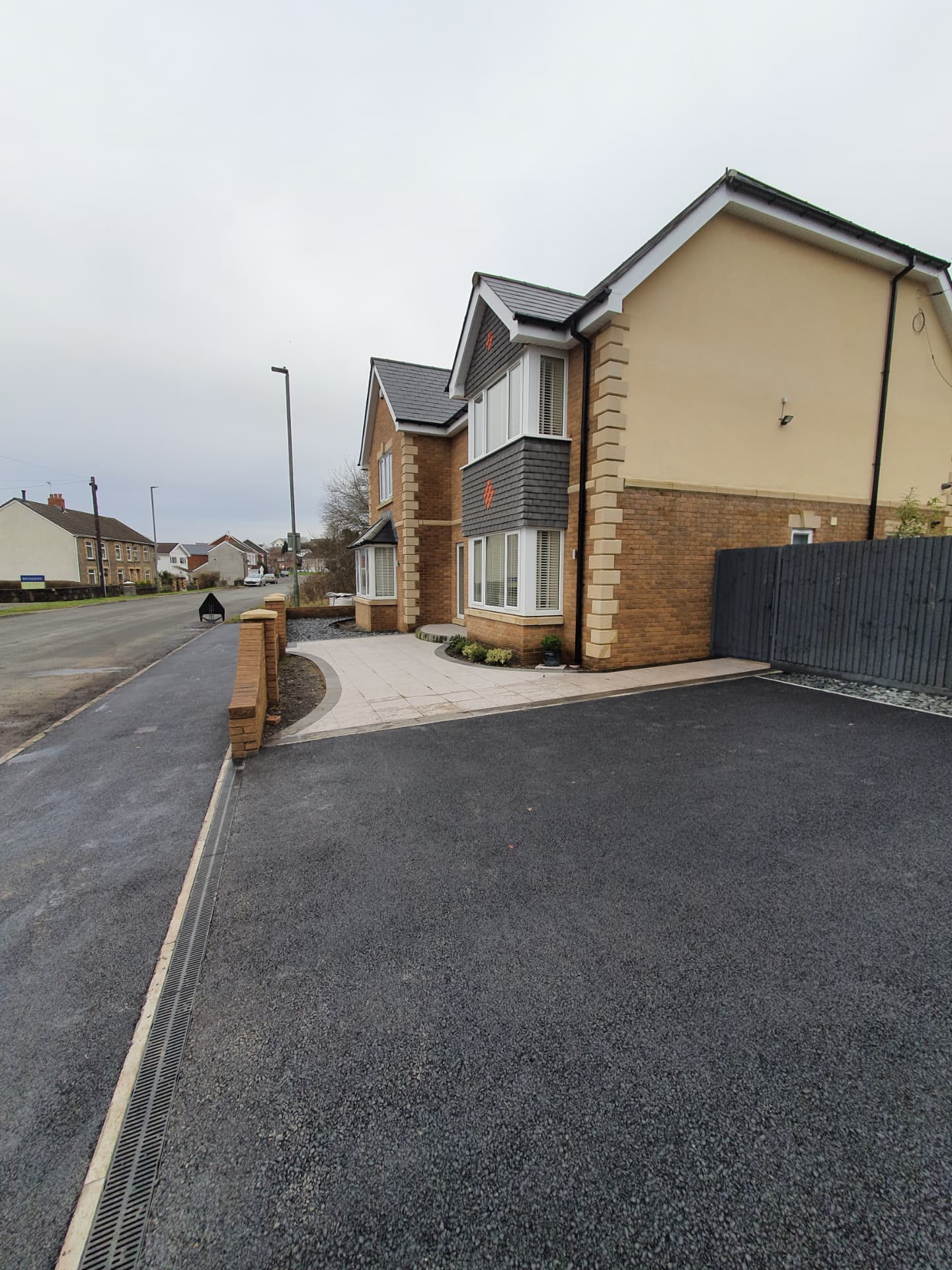 New tarmac driveway and paved footpath leading to a detached family house